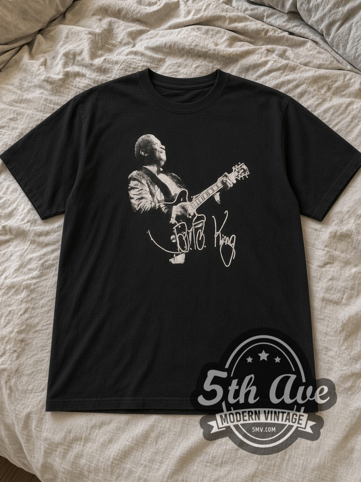 Black B.B. King Guitar Signature Portrait Vintage Band T-Shirt laid flat on a linen bed