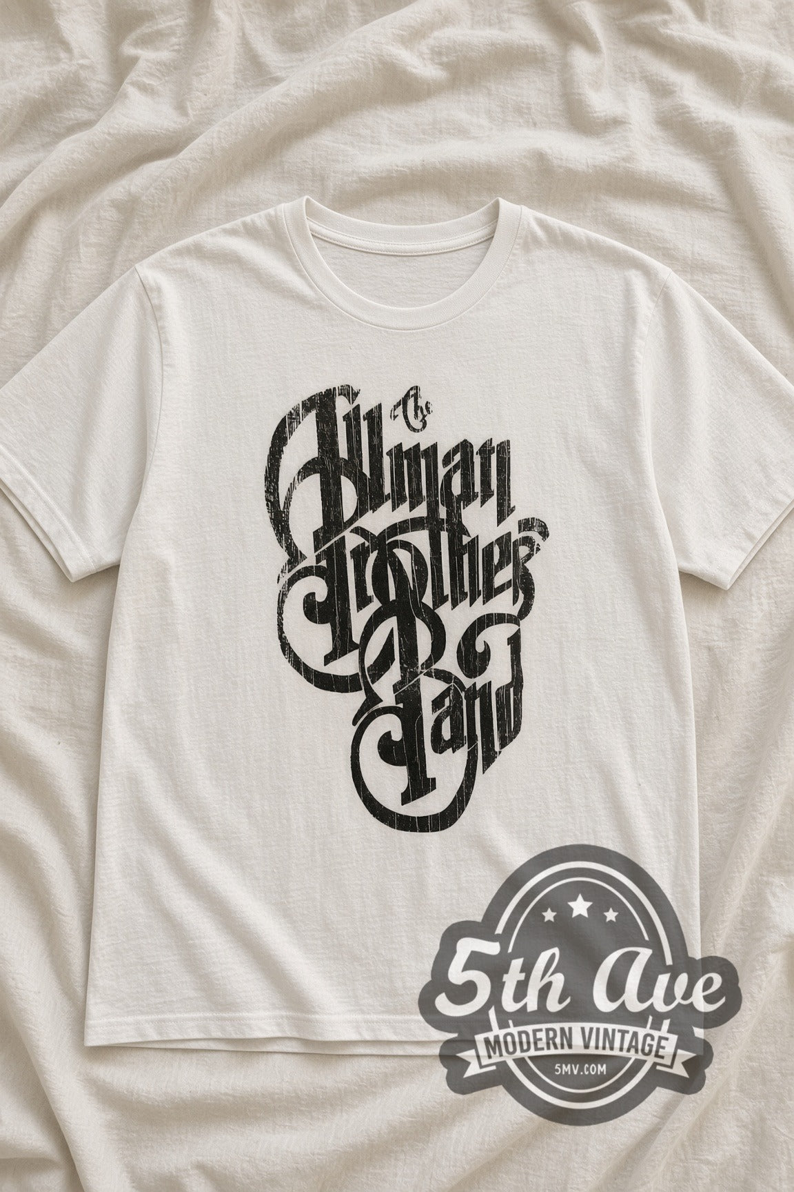 The Allman Brothers Band Black Distressed Script Logo vintage band t-shirt in white, laid flat on a bed