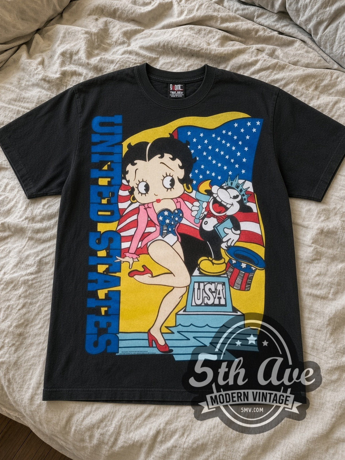 Betty Boop USA Statue of Liberty cartoon tee in black laid flat on a bed, front artwork