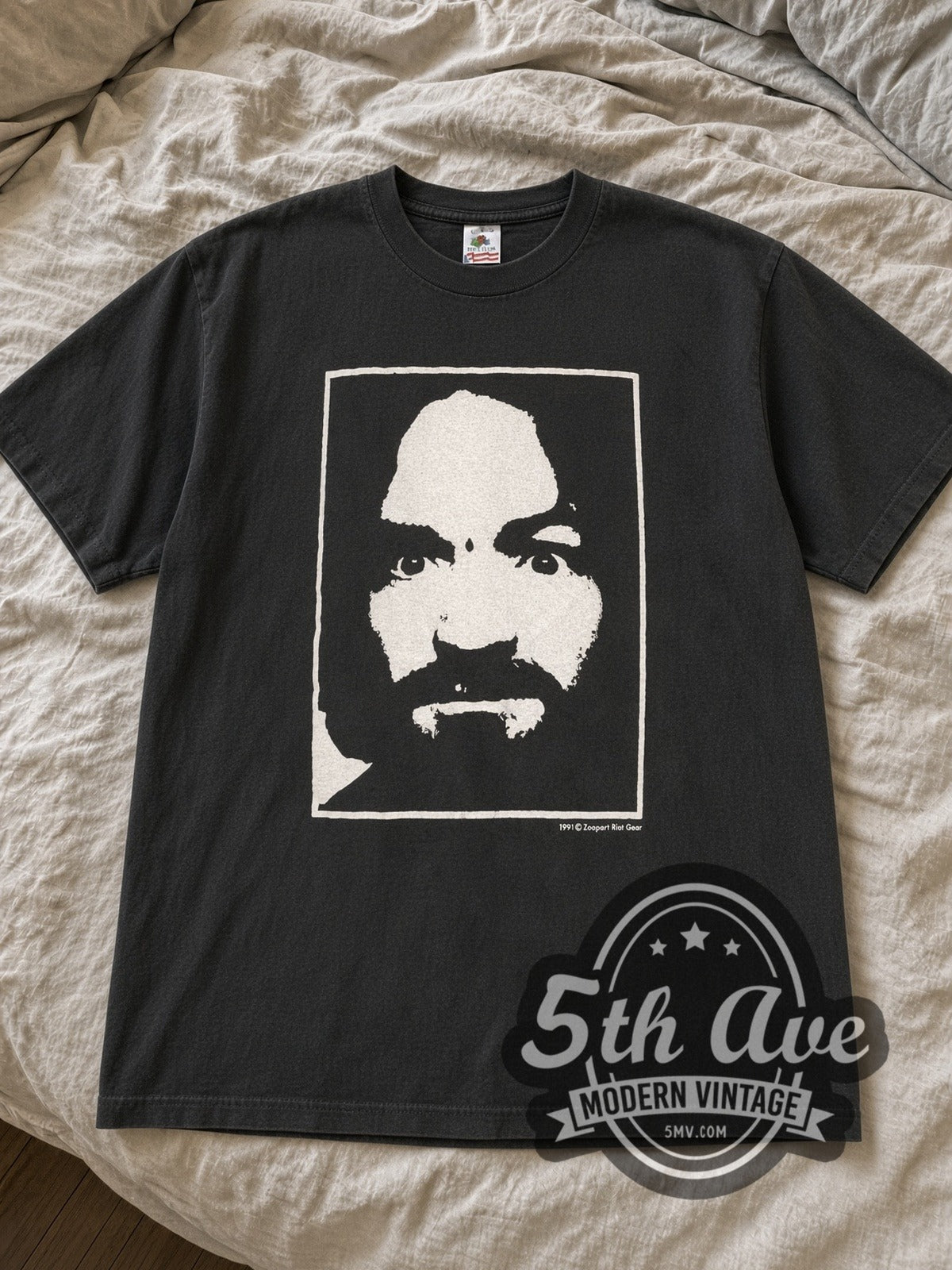 Black Charlie Dont Surf graphic tee laid flat on linen bed