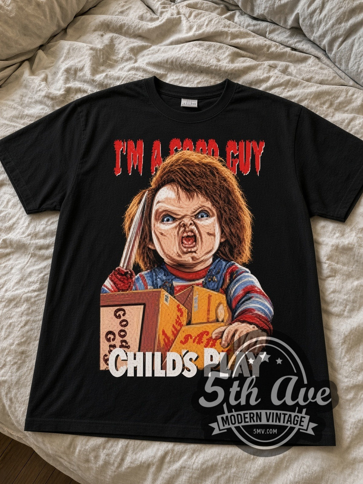 Child's Play Chucky I'm a Good Guy black graphic tee laid flat on linen bed