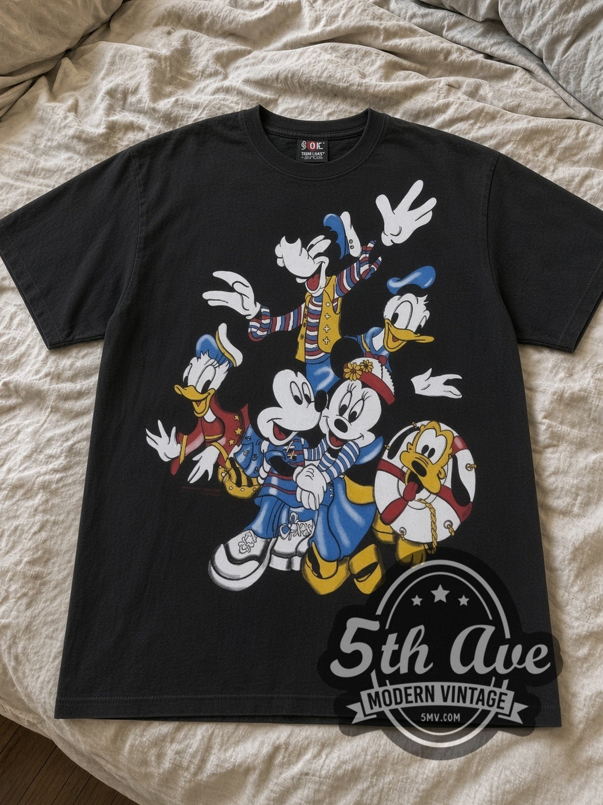 Disney Mickey Friends Nautical Group cartoon tee in black laid flat on a bed, front artwork
