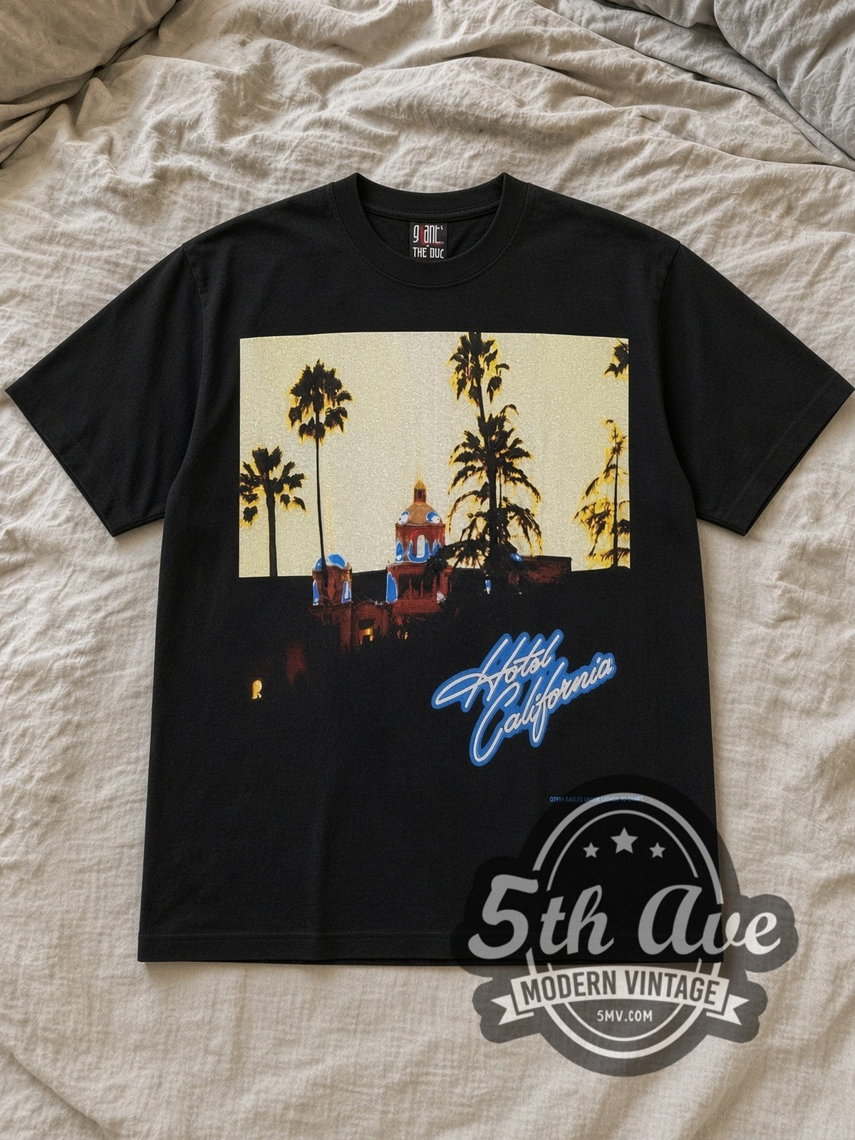 Black Eagles Hotel California Tribute Vintage Band T-Shirt laid flat on a linen bed