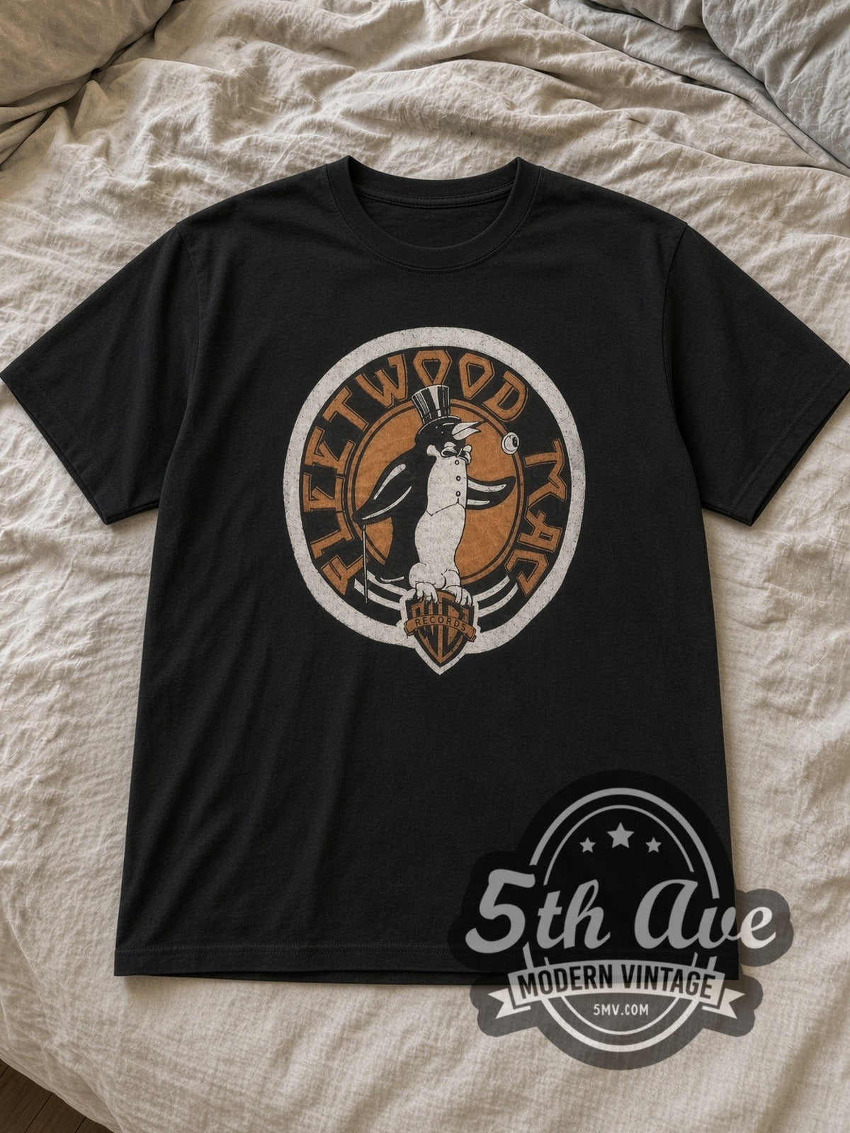 Black Fleetwood Mac Penguin Logo Vintage Band T-Shirt laid flat on a linen bed
