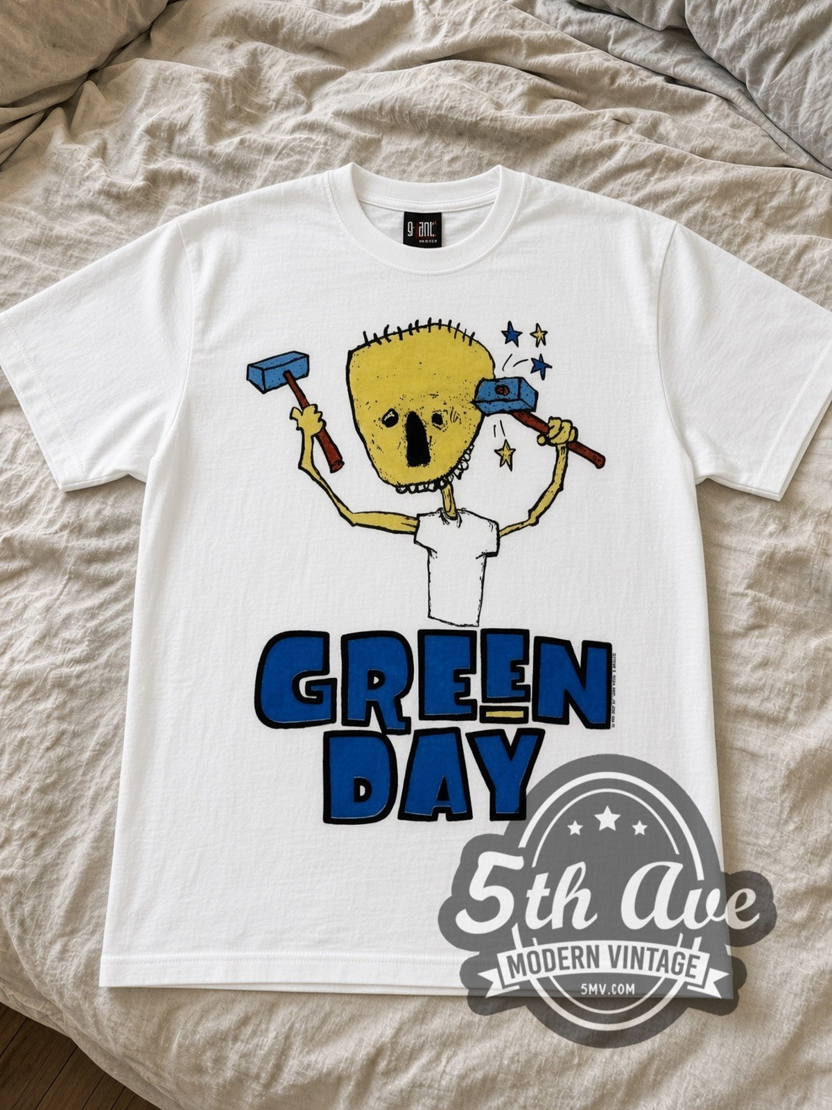 Green Day Nimrod Hammer Skull band t-shirt in white laid flat on a bed, front artwork