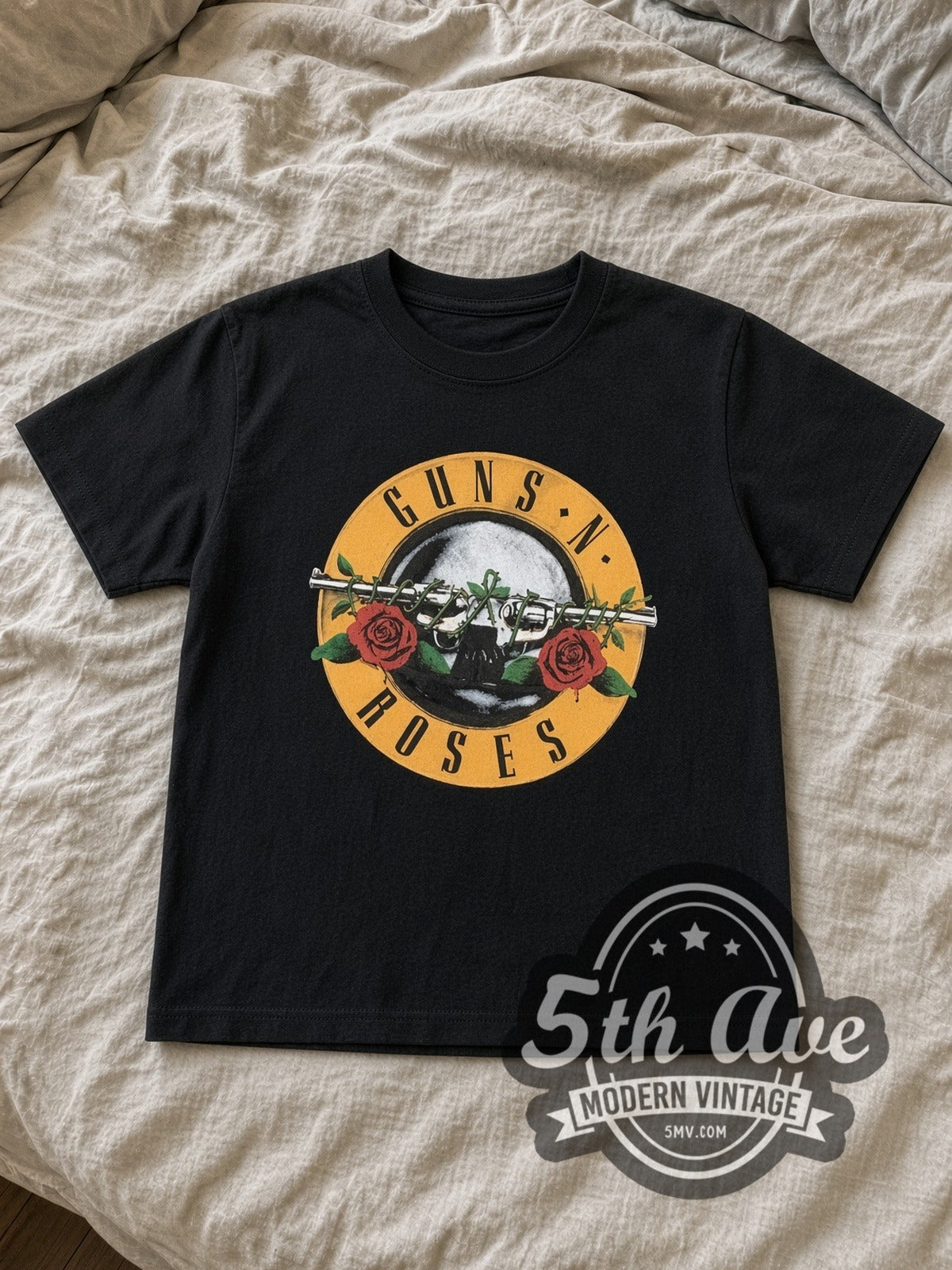 Guns N' Roses Bullet Logo Was Here kids band tee in black laid flat on a bed, front artwork