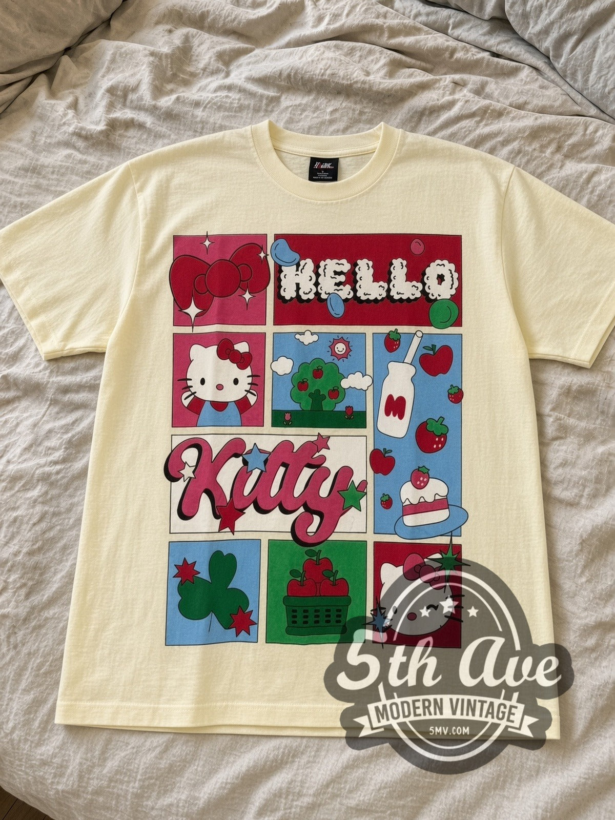 Cream Hello Kitty Strawberry Grid & Polaroid Photos tee laid flat on linen bed