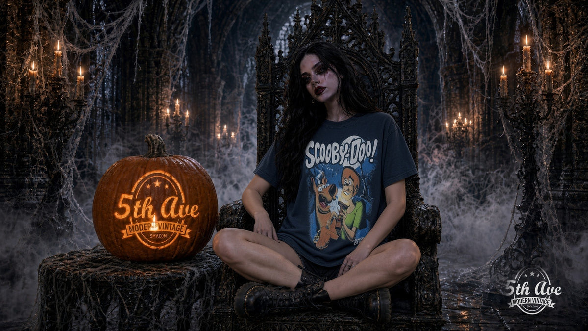 Model in faded navy Scooby-Doo Where Are You Zombie Night tee seated on a gothic throne beside a carved 5th Ave pumpkin