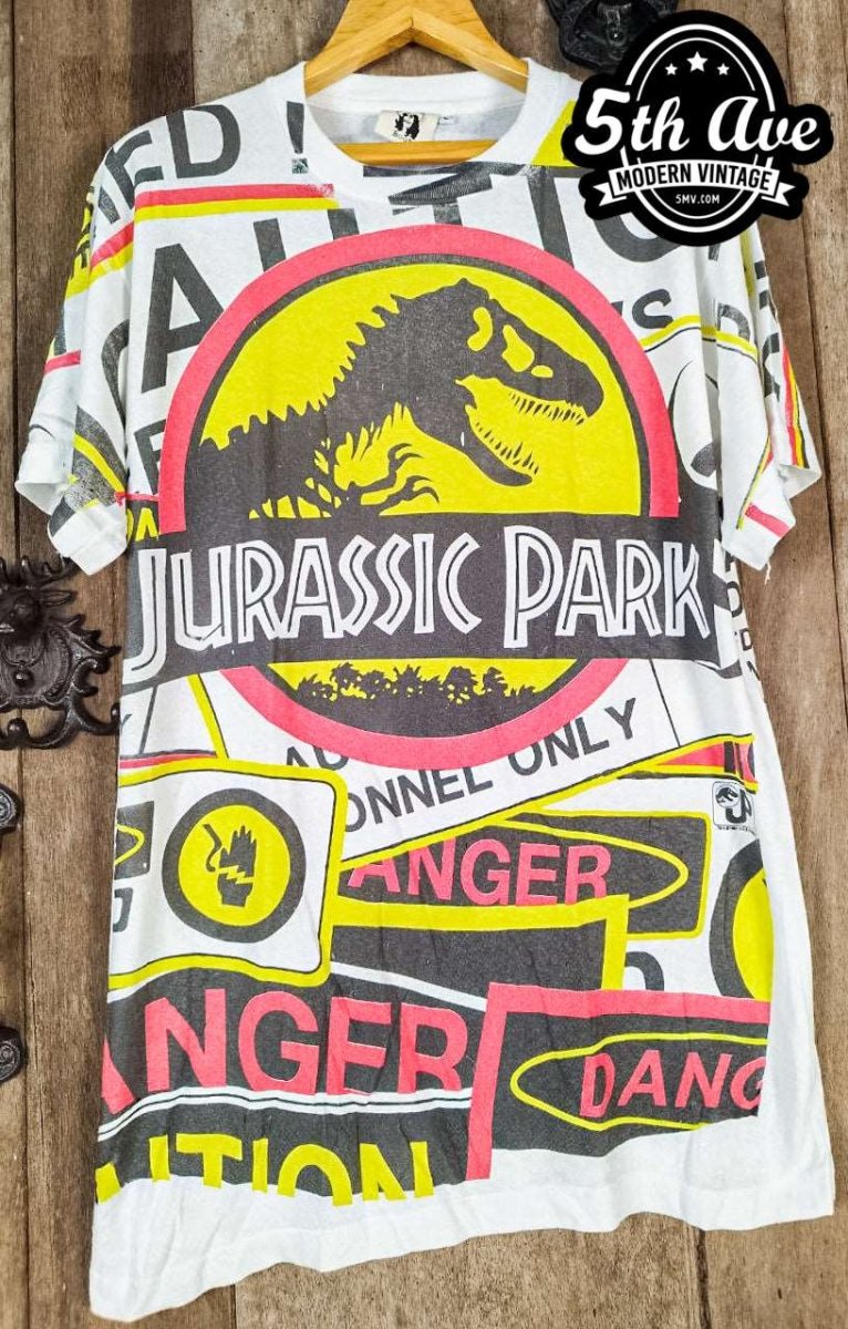 Jurassic Adventure: Distressed Cotton T-Shirt with All-Over Jurassic Park Print and 30-Day Satisfaction Guarantee - Vintage Band Shirts