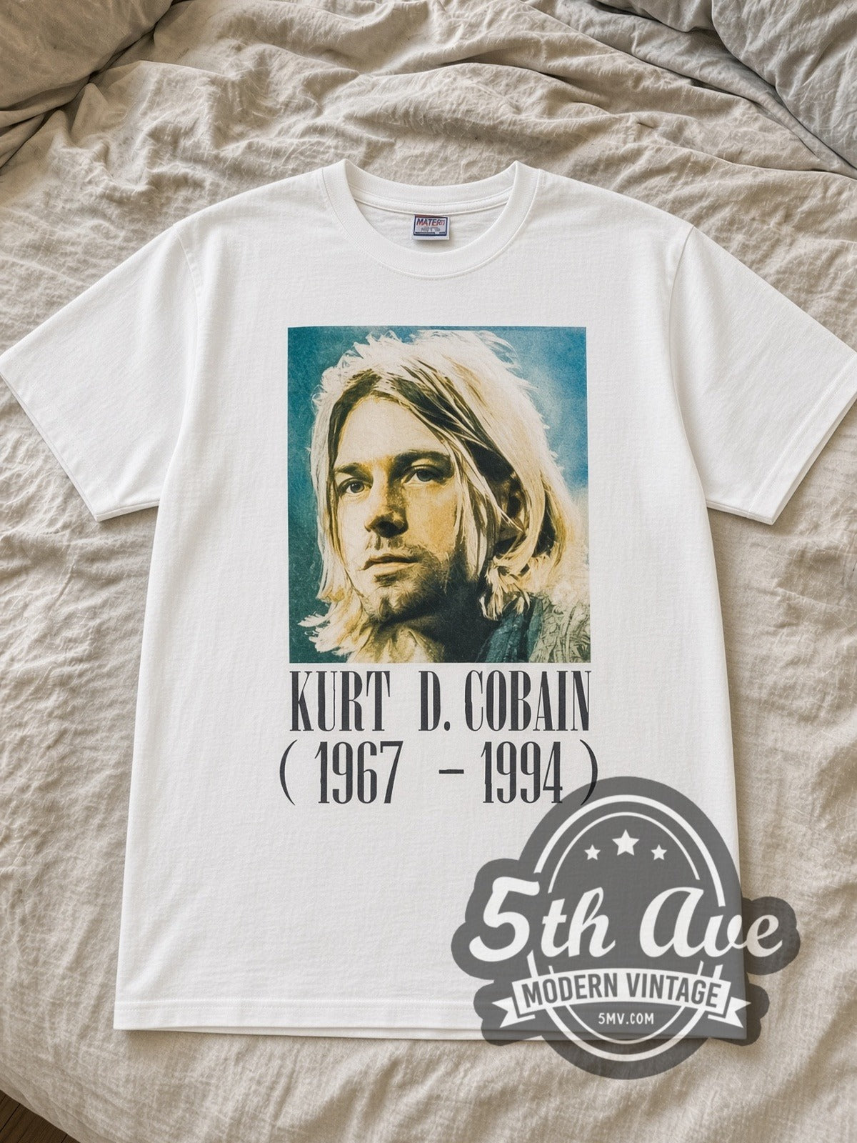 White Kurt Cobain 1967 1994 Vintage Band T-Shirt laid flat on a linen bed