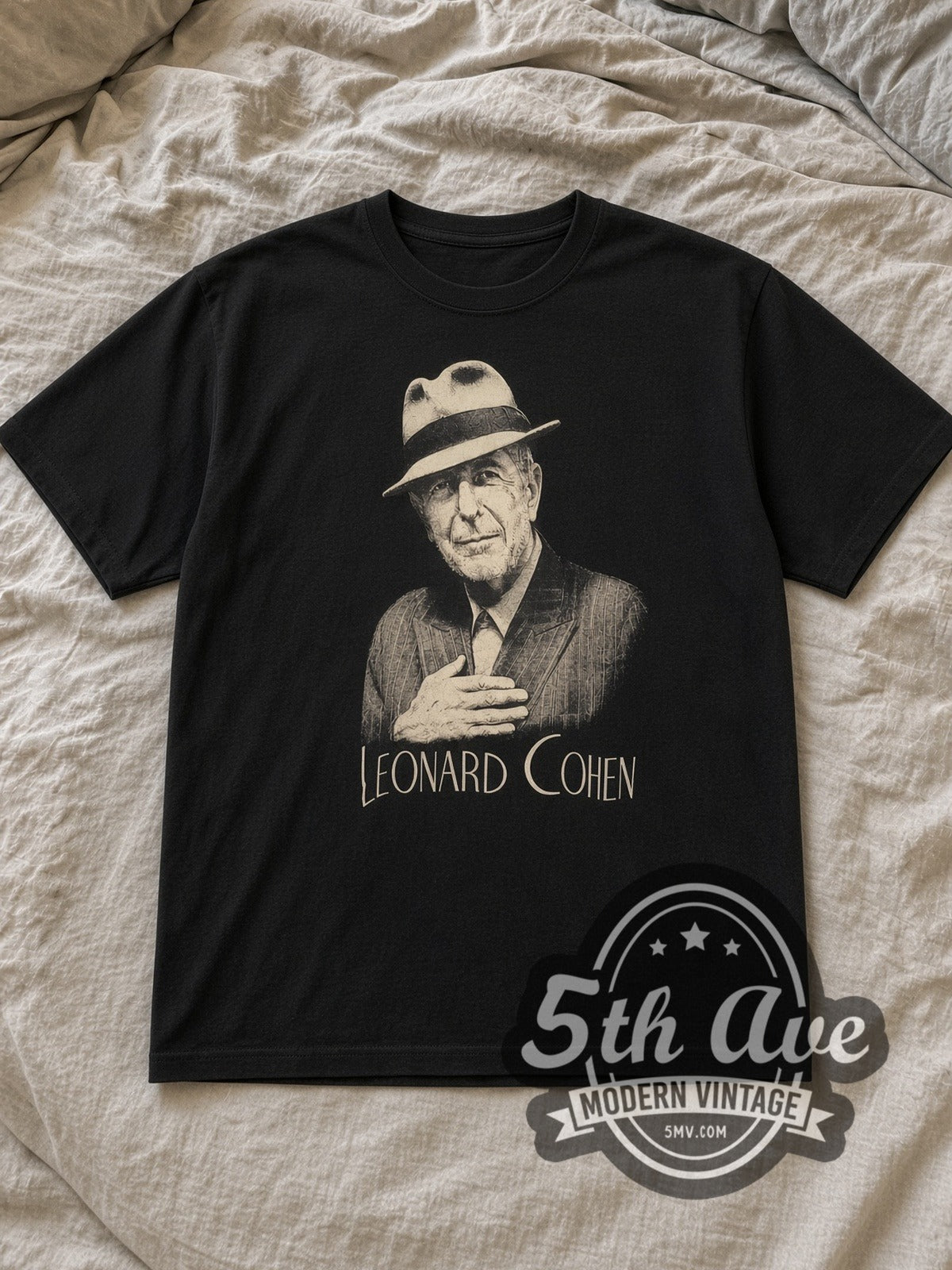 Black Leonard Cohen Inspired Portrait Cotton Vintage Band T-Shirt laid flat on a linen bed
