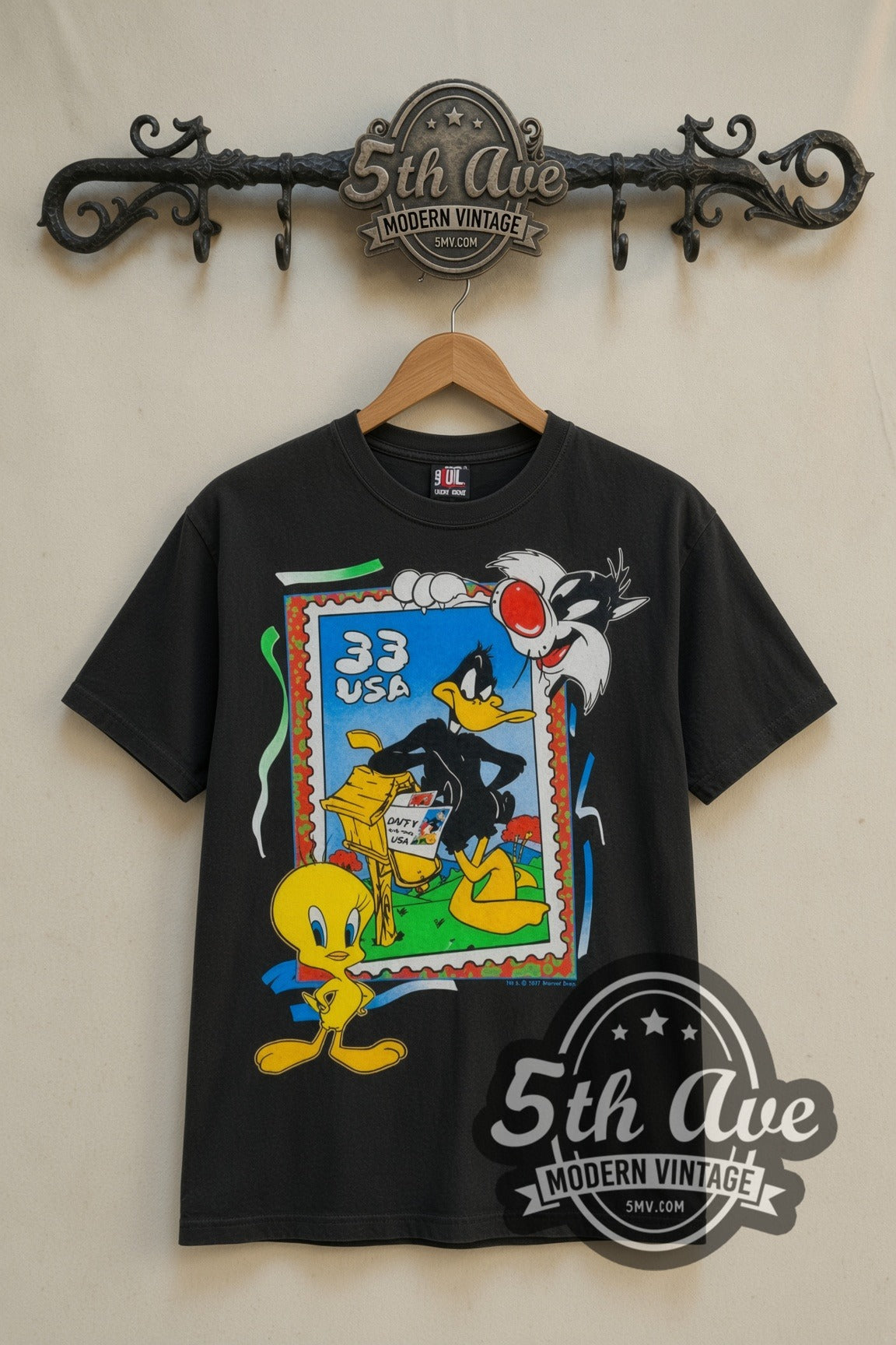 Looney Tunes 33 USA Stamp Tweety Sylvester cartoon tee in black, front view on a display rack
