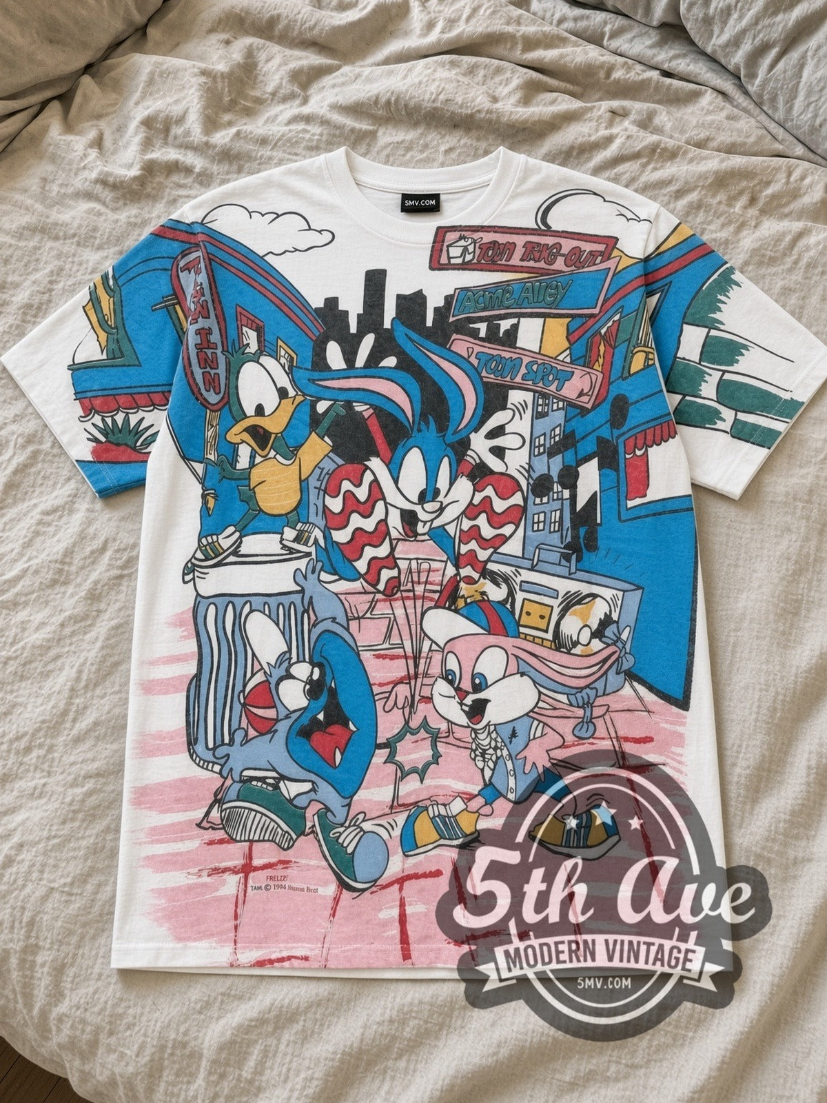White Looney Tunes All Over Print Vintage Cartoon T-Shirt laid flat on a linen bed