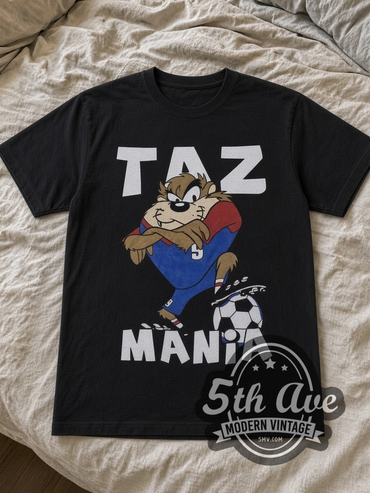 Looney Tunes Taz Soccer Champions cartoon tee in black laid flat on a bed, front artwork