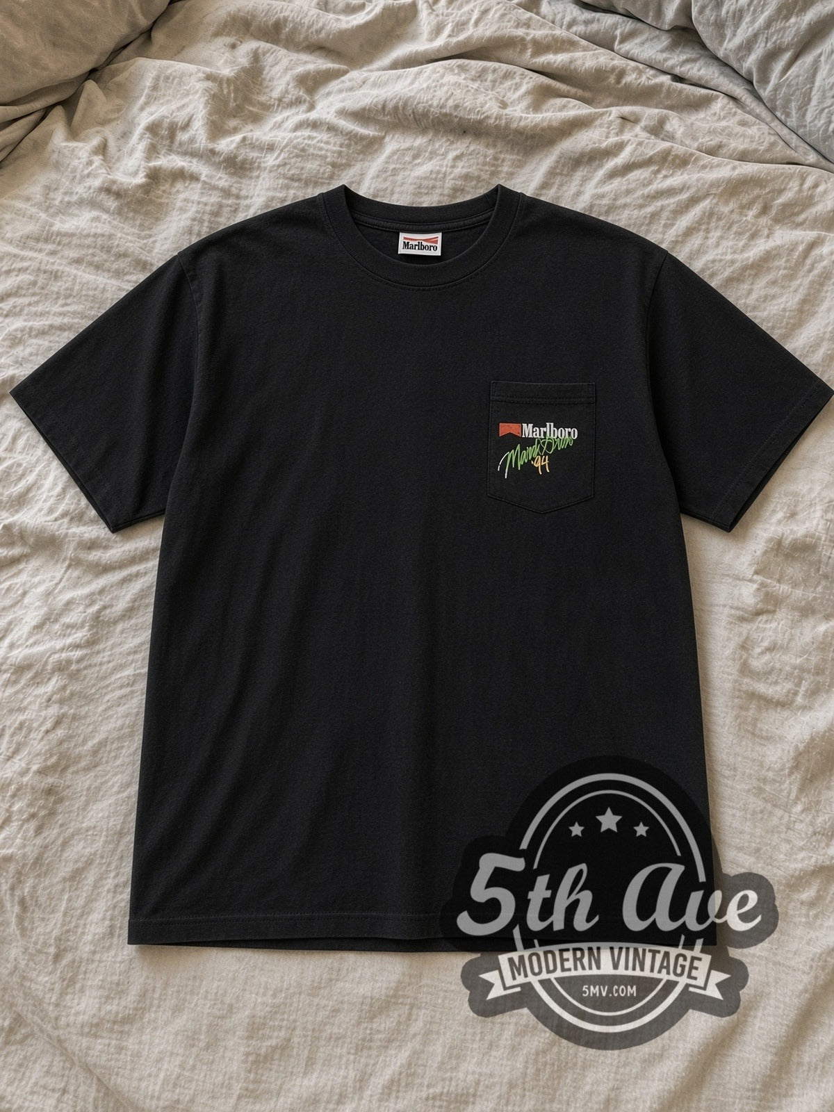 Black Marlboro Mardi Gras 1994 Vintage Graphic T-Shirt laid flat on a linen bed