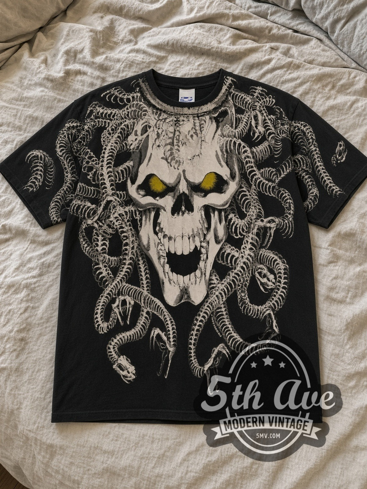 Black Medusa Skull All Over Print Vintage Graphic T-Shirt laid flat on a linen bed