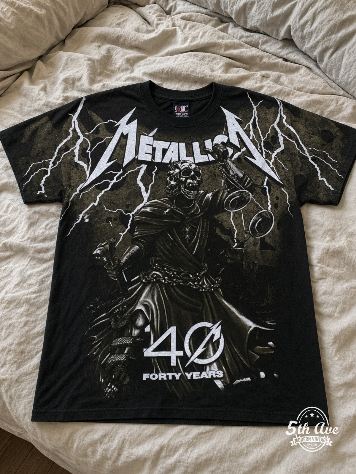 Metallica 40 Years Lady Justice all over print vintage tee laid on bed