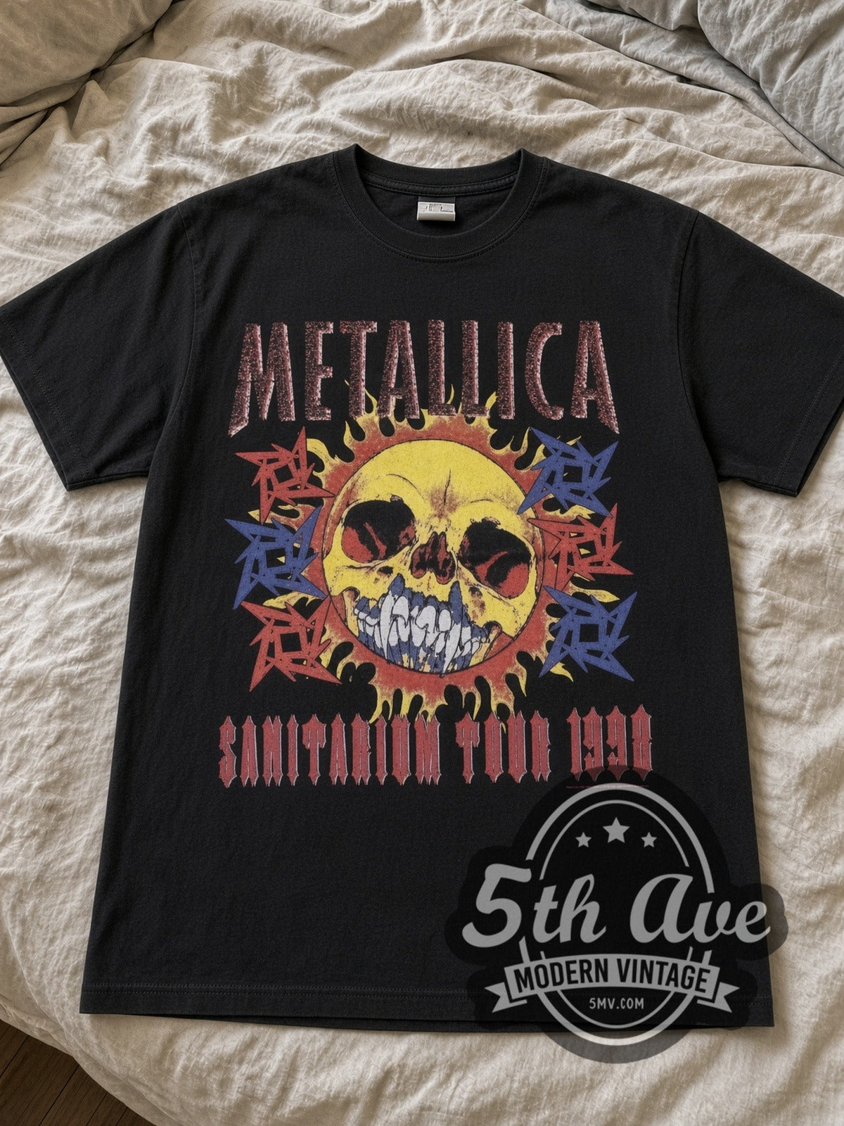 Metallica Sanitarium Skull 1998 Tour Dates band t-shirt in black laid flat on a bed, front artwork