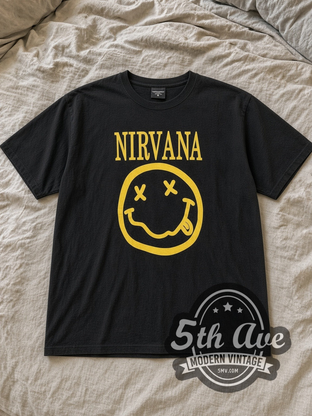 Black Nirvana Classic Yellow Smiley Face Logo Vintage Band T-Shirt laid flat on a linen bed