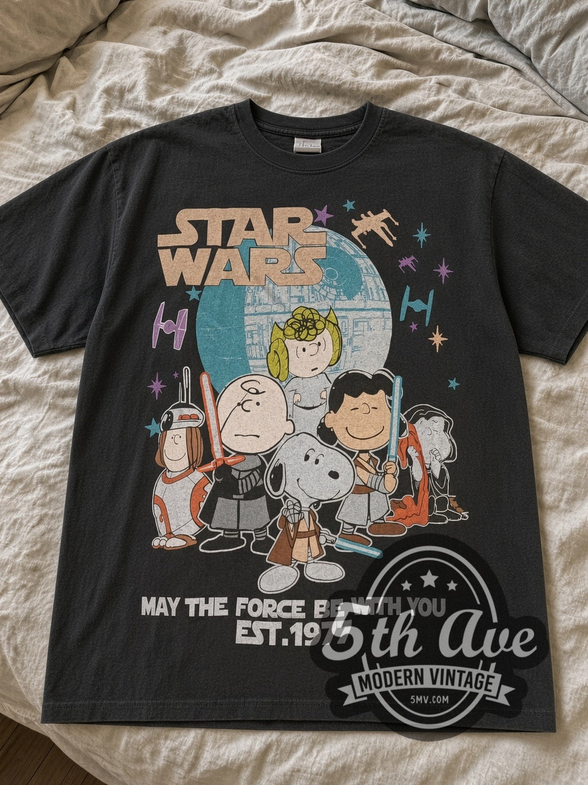 Faded black Peanuts x Star Wars May the Force Be With You Est. 1977 tee laid flat on linen bed