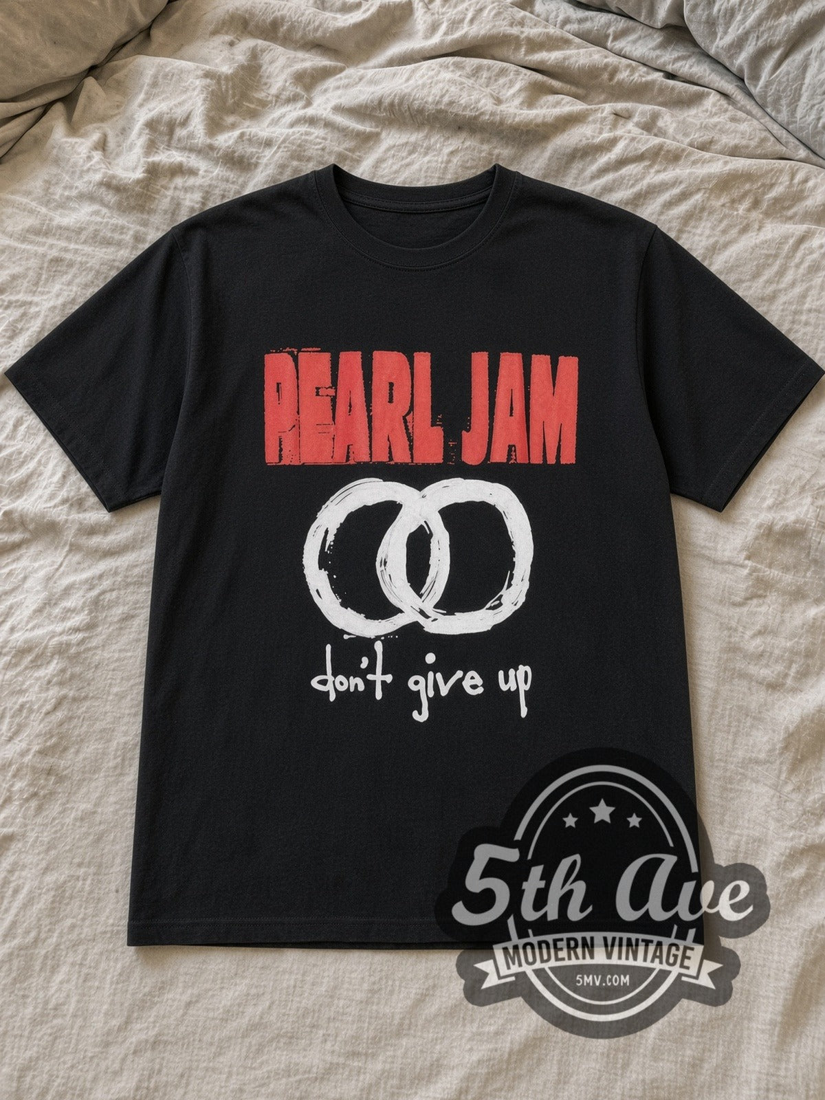 Black Pearl Jam Don't Give Up Vintage Band T-Shirt laid flat on a linen bed
