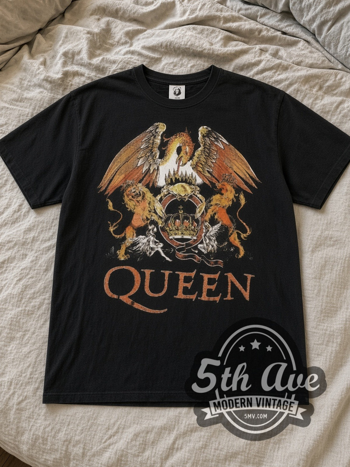 Black Queen Color Crest Orange Logo Vintage Band T-Shirt laid flat on a linen bed