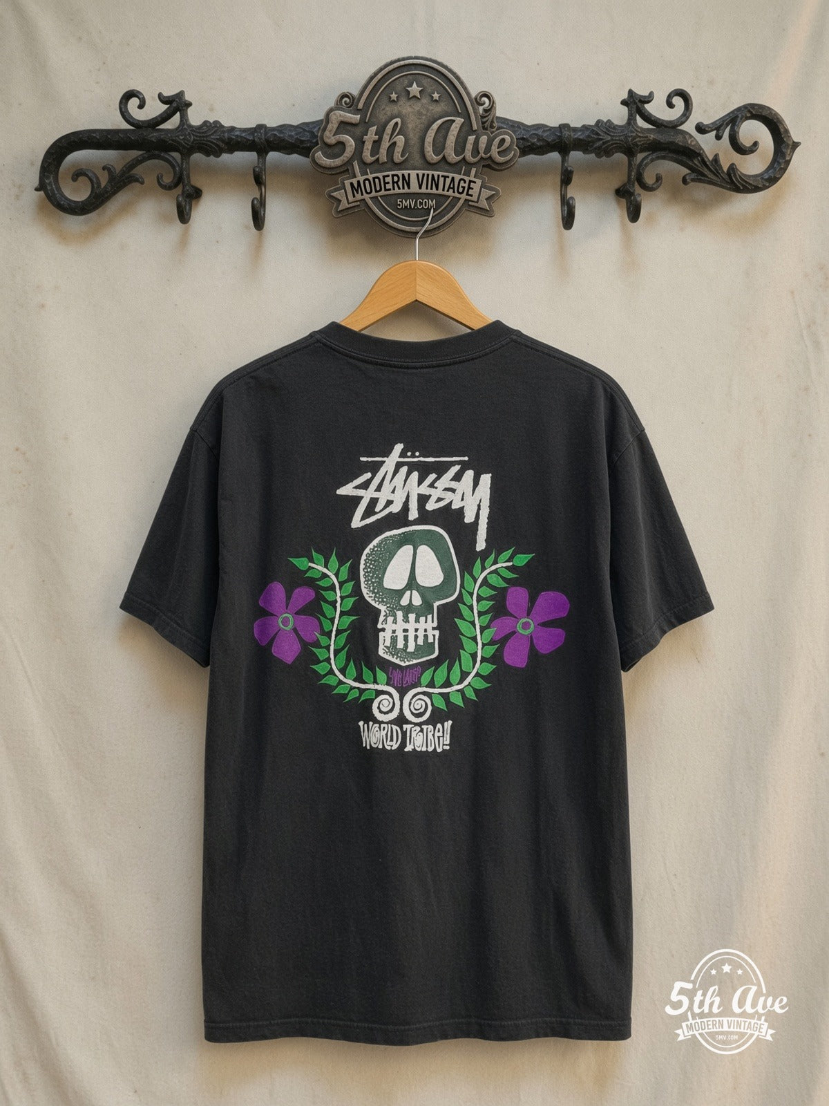Stussy – World Tribe Skull Crest – Vintage Graphic Tee — back on locked cream ornate 5th Ave rack
