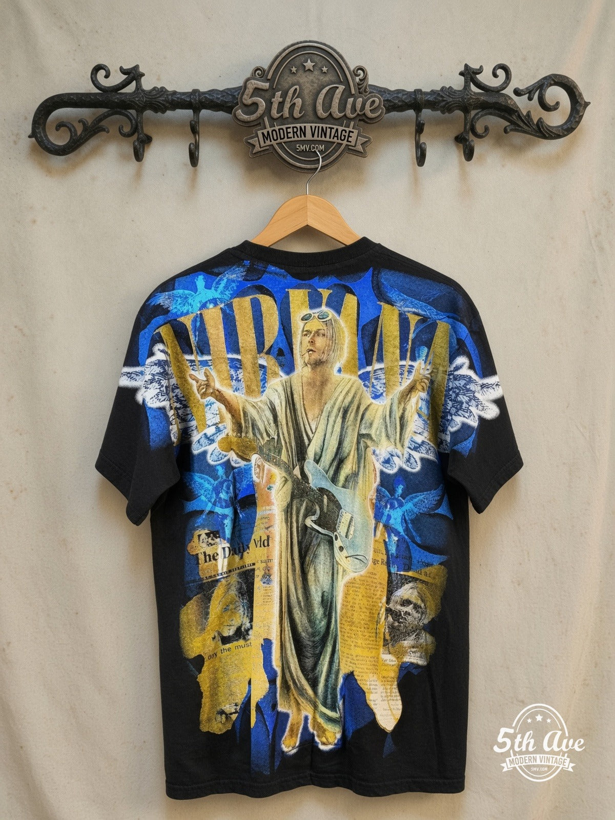 Kurt Cobain – Nirvana in The Daily World – All Over Print – Vintage Band T-Shirt — back on locked cream ornate 5th Ave rack