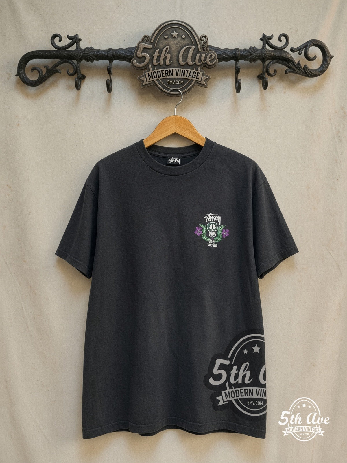 Stussy – World Tribe Skull Crest – Vintage Graphic Tee — front on locked cream ornate 5th Ave rack