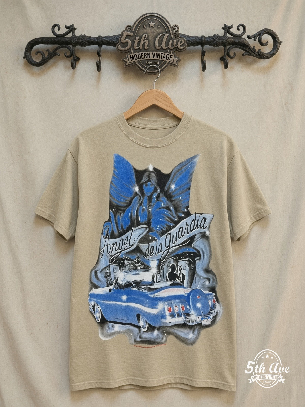 Rollin Hard Angel de la Guardia Lowrider graphic tee in sand, front view on a display rack