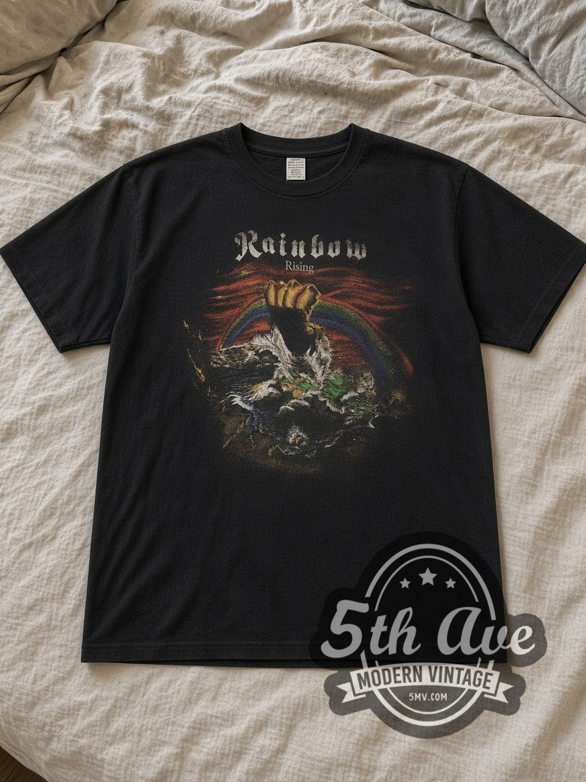 Black British rock supergroup Rainbow Rising Vintage Band T-Shirt laid flat on a linen bed