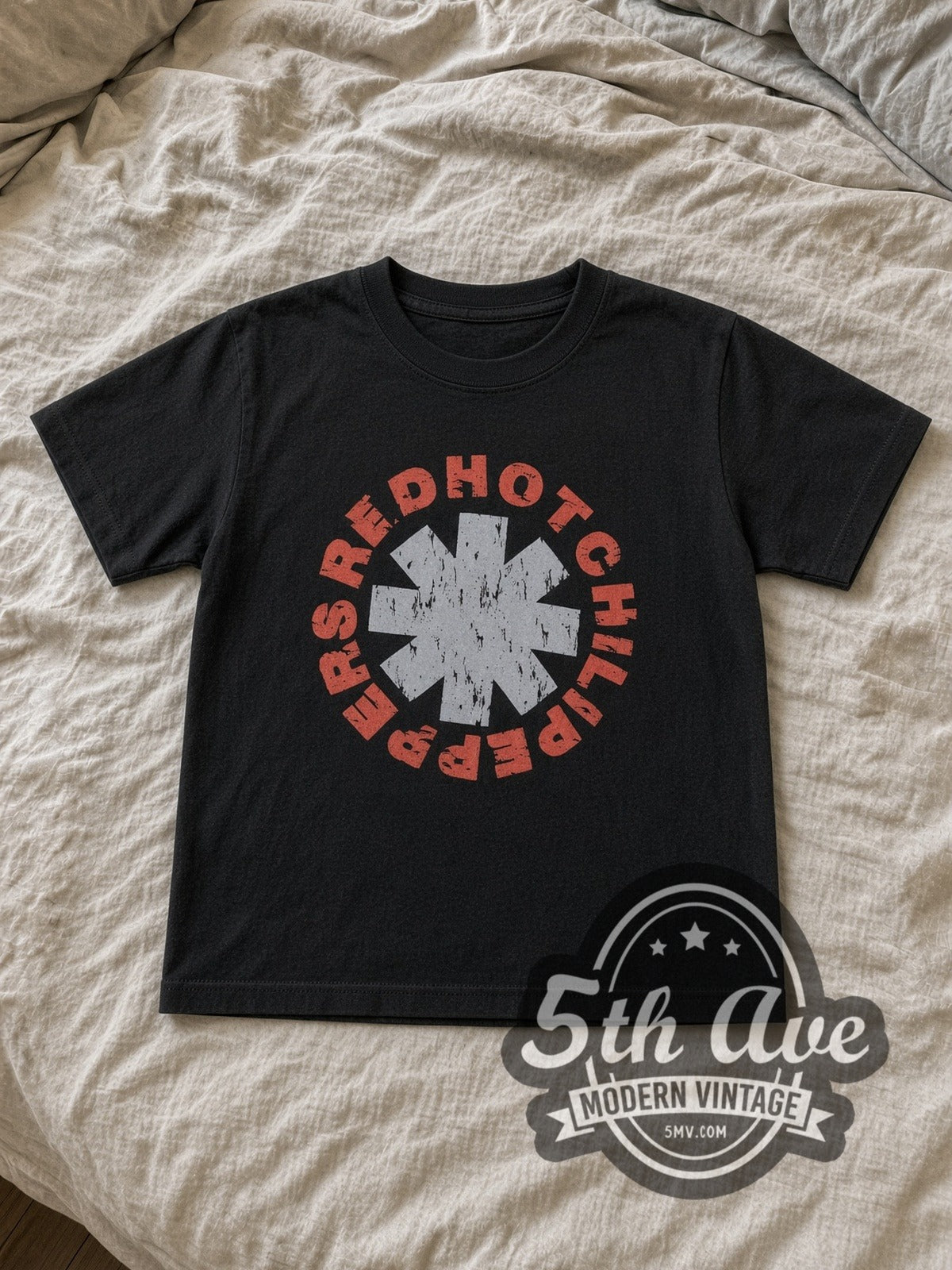 Red Hot Chili Peppers Asterisk Circle kids band tee in black laid flat on a bed, front artwork