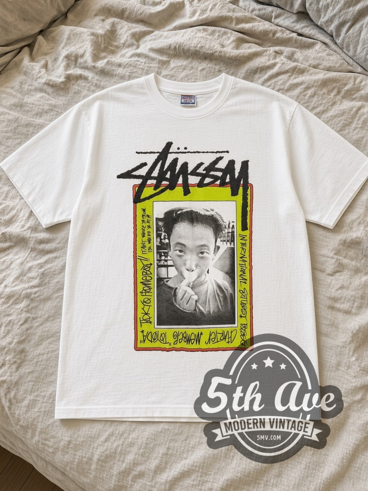White Stussy Toyoda Tokyo Homeboy Vintage Graphic T-Shirt laid flat on a linen bed