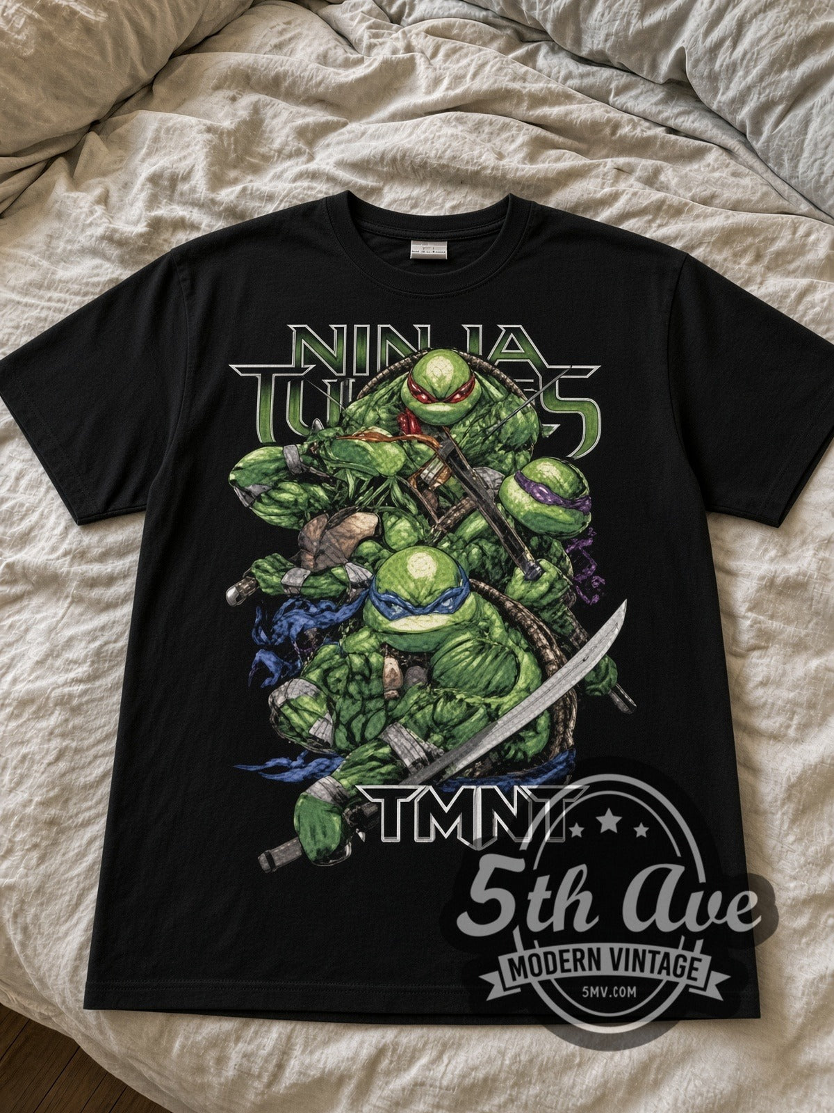 Teenage Mutant Ninja Turtles Four Turtles black graphic tee laid flat on linen bed
