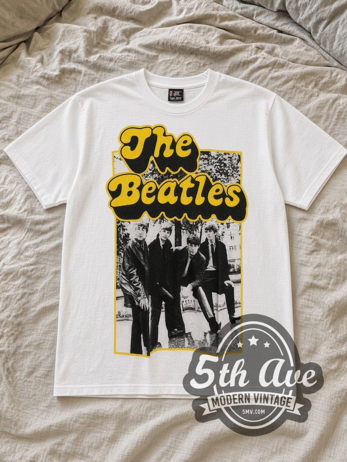 White The Beatles Yellow Bubble Font Early Photo Vintage Band T-Shirt laid flat on a linen bed
