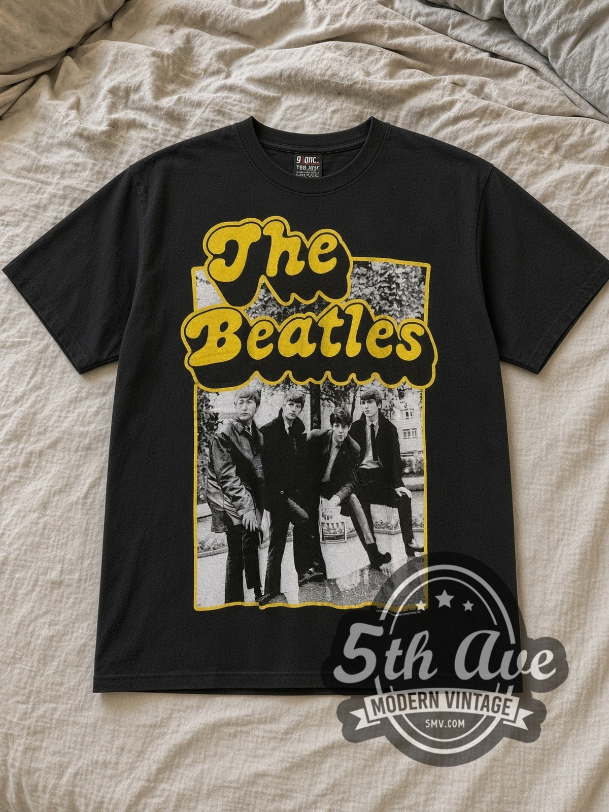 Black The Beatles Yellow Border Early Suits Photo Vintage Band T-Shirt laid flat on a linen bed