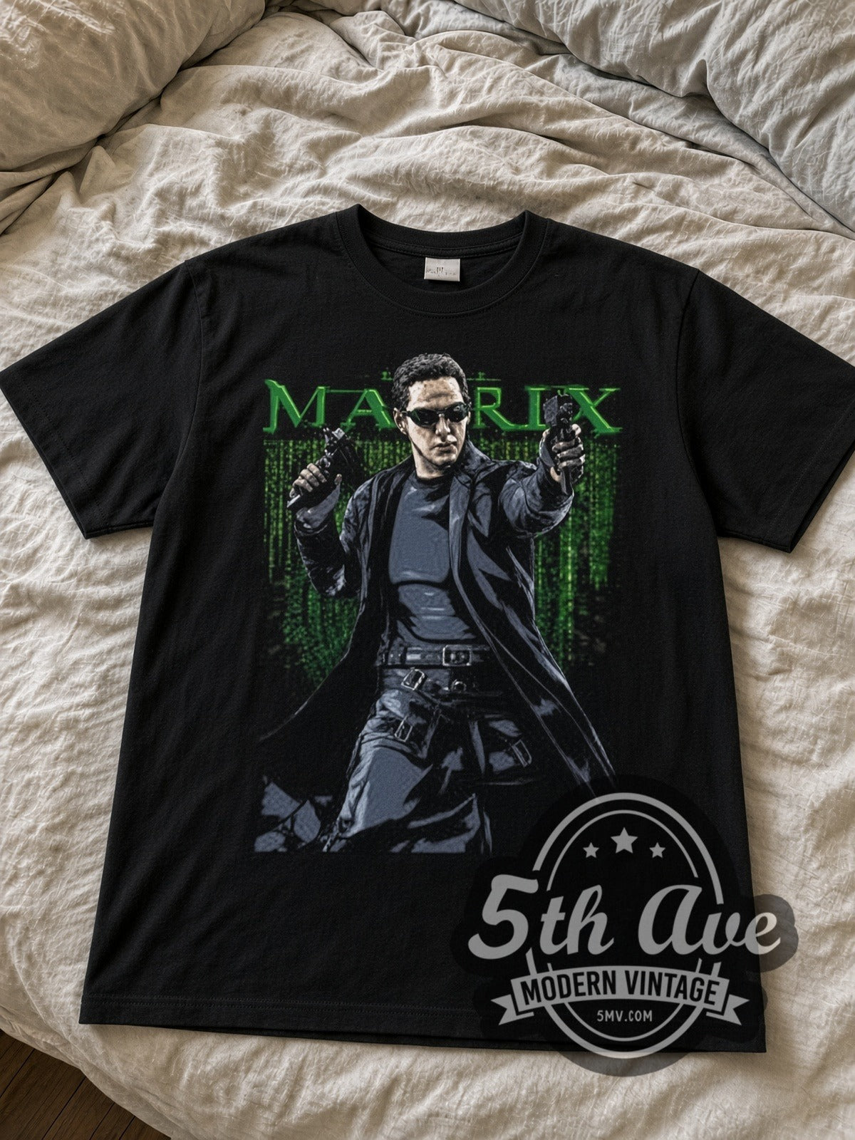 The Matrix Neo with Pistols black graphic tee laid flat on linen bed