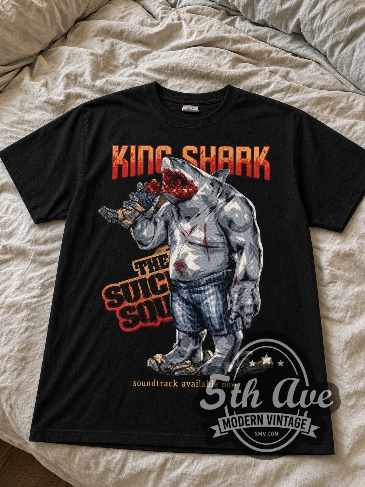 The Suicide Squad King Shark black graphic tee laid flat on linen bed