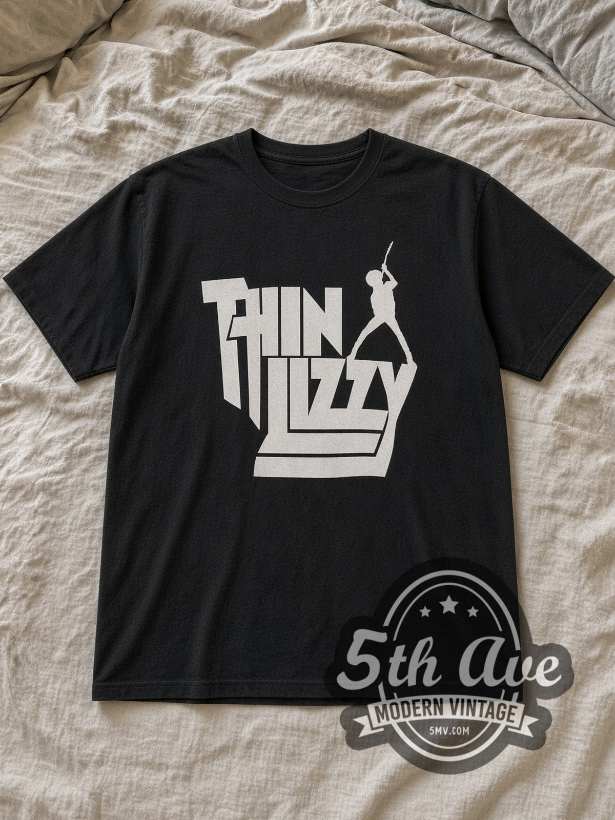 Black Thin Lizzy Stacked White Logo Guitarist Silhouette Vintage Band T-Shirt laid flat on a linen bed