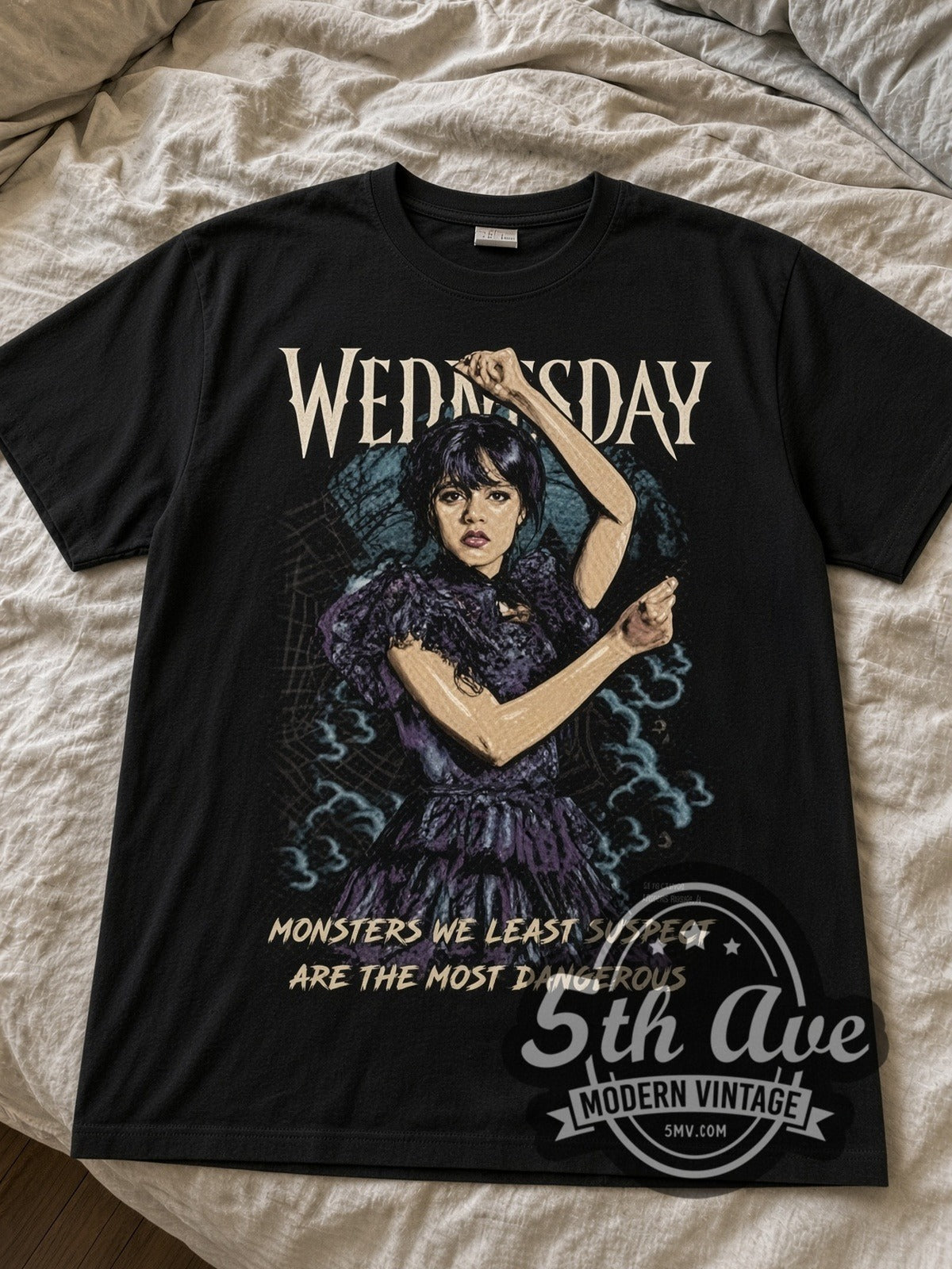 Wednesday Dancing Wednesday Monsters We Least Suspect black graphic tee laid flat on linen bed