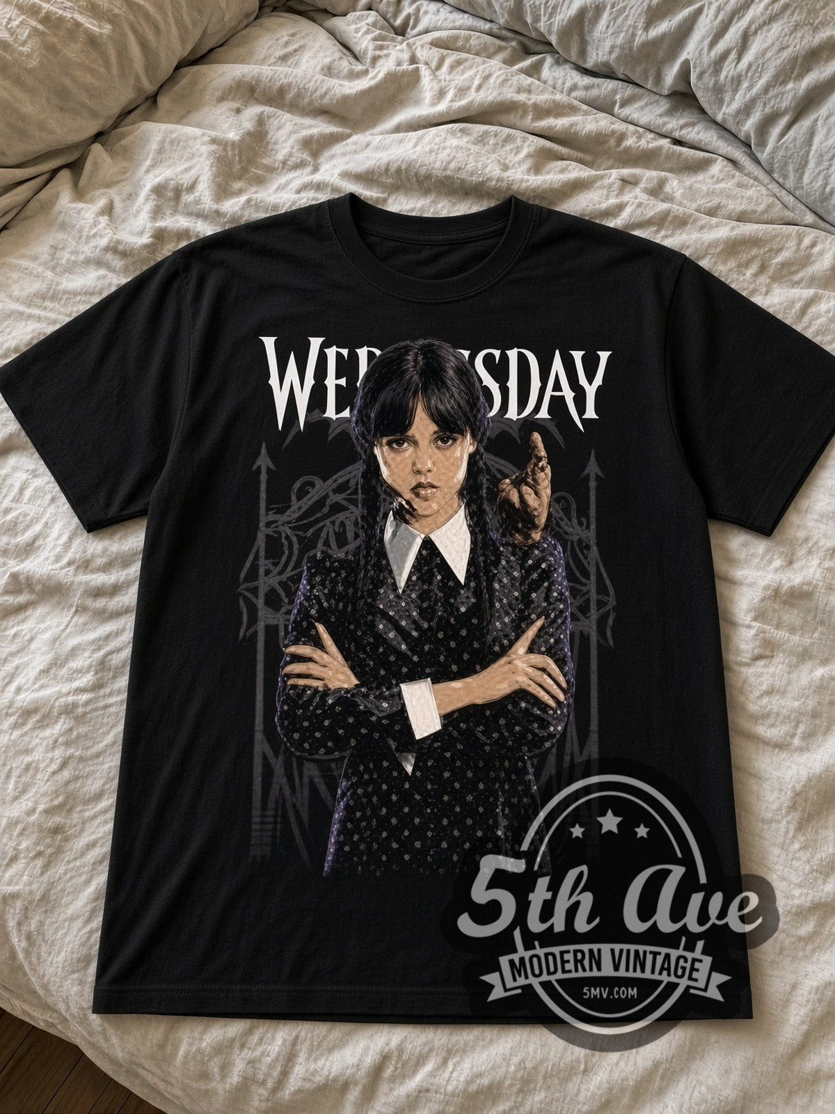 Wednesday Addams with Thing black graphic tee laid flat on linen bed